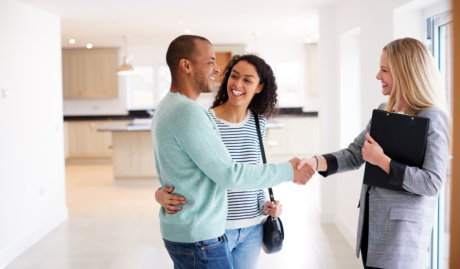 Female Realtor Shaking Hands With Couple Interested In Buying House